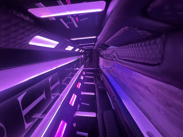 The Royale party bus interior with purple LED lighting and extended wrap-around seating
