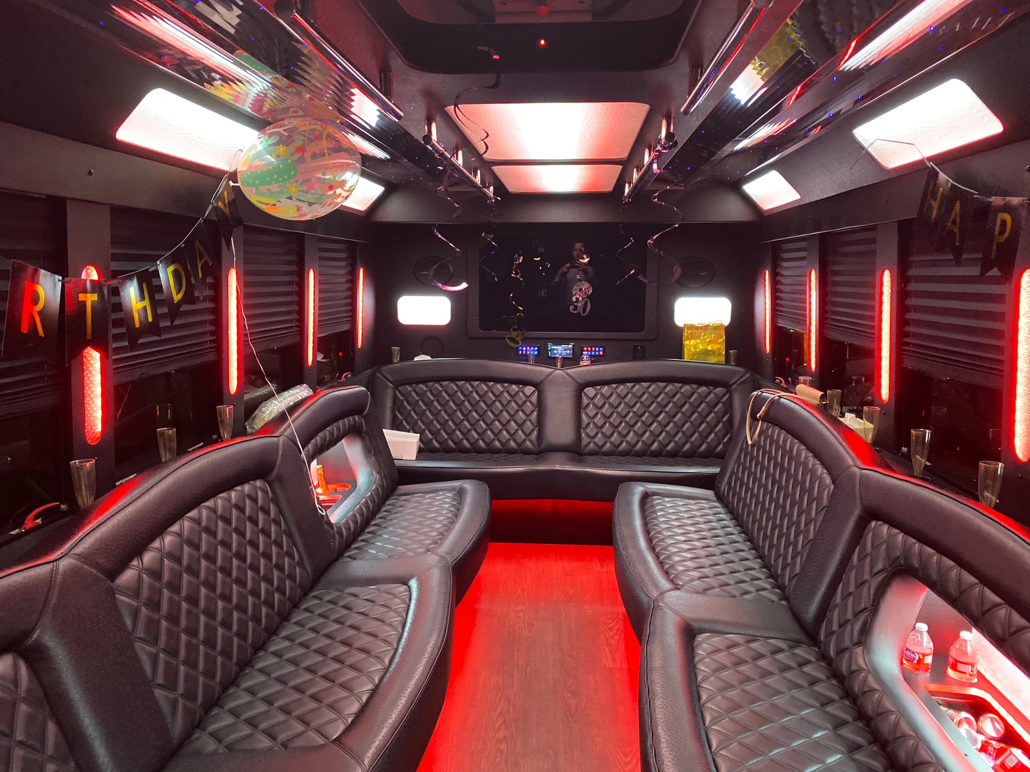 The Executive party bus interior with red LED lighting and diamond-stitched leather seating