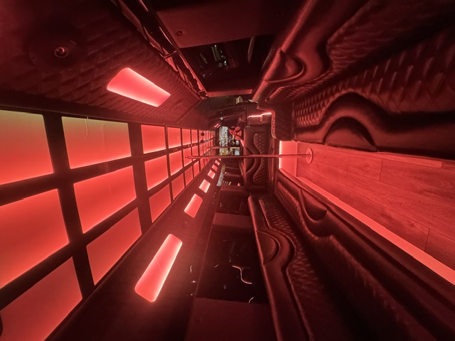 The Grande party bus interior with red LED ceiling lighting and wrap-around seating